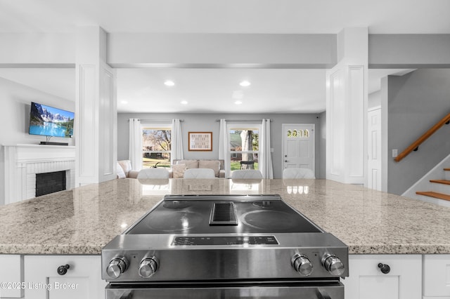 kitchen with open floor plan, electric stove, a fireplace, and light stone countertops