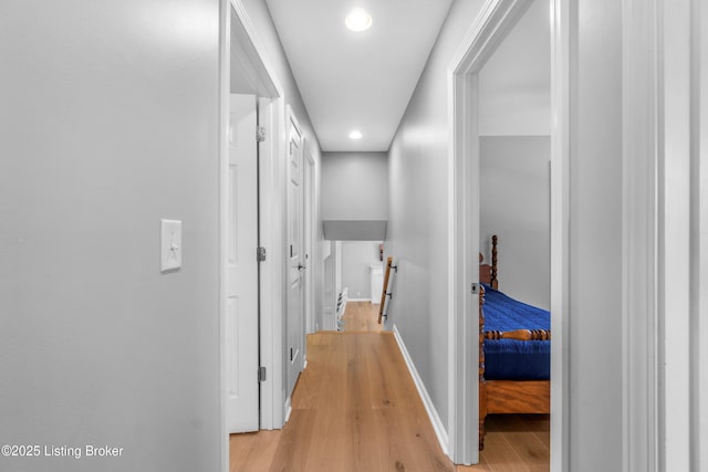 hall featuring recessed lighting, baseboards, light wood-style flooring, and an upstairs landing