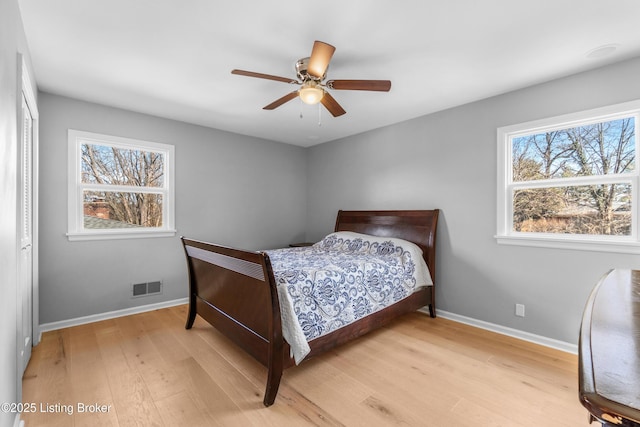 bedroom with ceiling fan, light wood-style flooring, visible vents, and baseboards