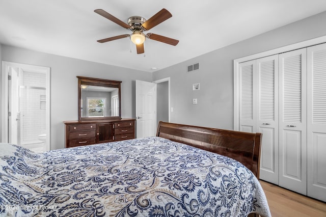 bedroom featuring a closet, visible vents, a ceiling fan, ensuite bath, and wood finished floors