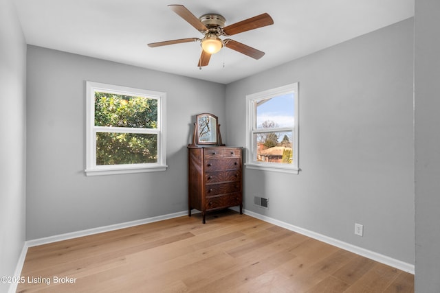 unfurnished room featuring light wood-style floors, baseboards, visible vents, and ceiling fan