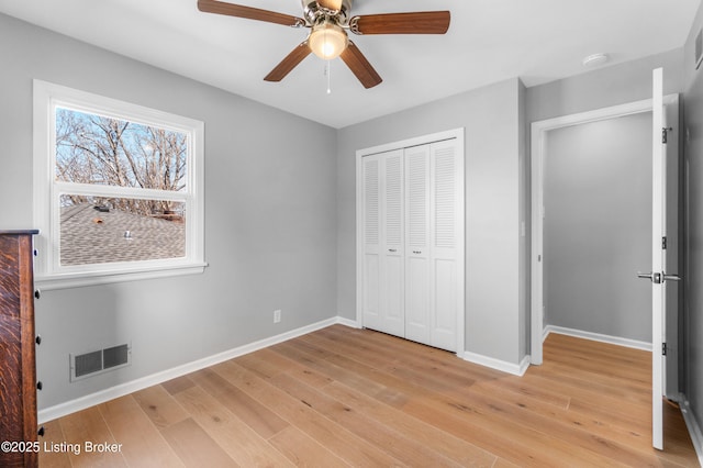 unfurnished bedroom with light wood finished floors, baseboards, visible vents, and a closet