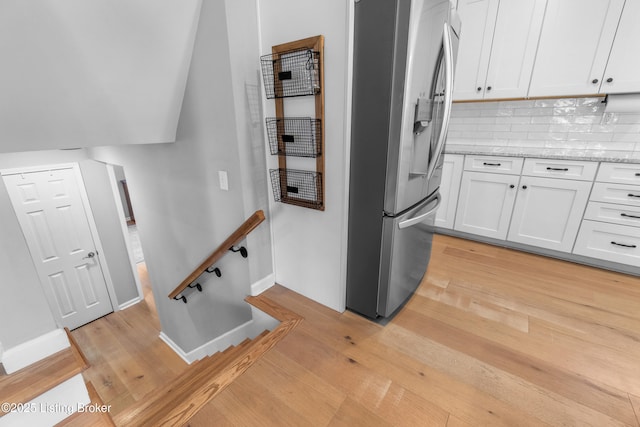 kitchen featuring light wood-type flooring, tasteful backsplash, white cabinetry, and stainless steel fridge with ice dispenser