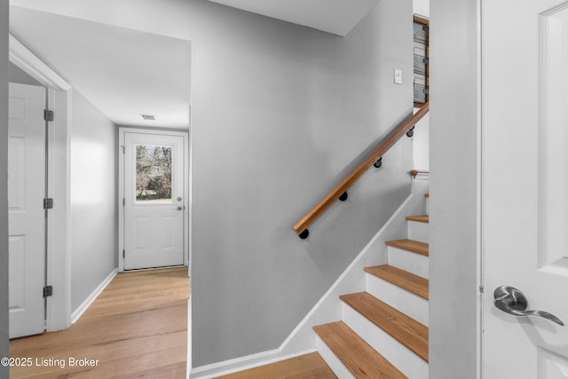 stairway with visible vents, baseboards, and wood finished floors