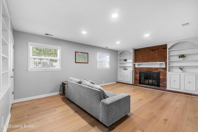 living area with light wood finished floors, built in shelves, a fireplace, and baseboards