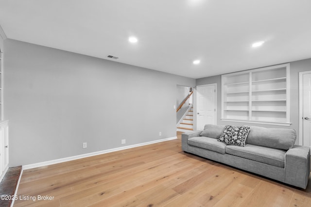 living area with hardwood / wood-style flooring, baseboards, stairs, and visible vents