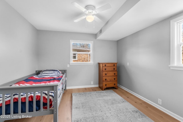 bedroom featuring a ceiling fan, visible vents, baseboards, and wood finished floors