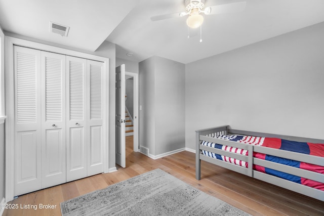 bedroom featuring a closet, visible vents, baseboards, and wood finished floors