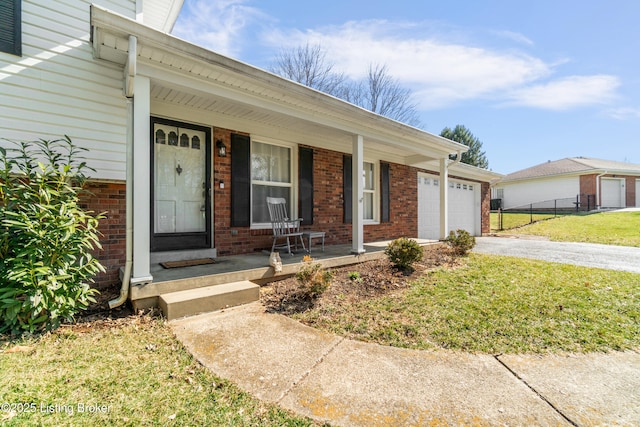 view of front facade featuring covered porch, a garage, brick siding, driveway, and a front yard