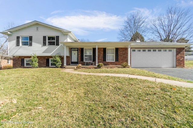 tri-level home featuring driveway, an attached garage, a front lawn, and brick siding