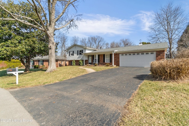 split level home featuring a garage, a front yard, brick siding, and aphalt driveway