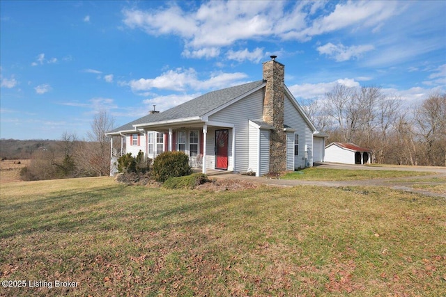 view of front facade with an outbuilding, a porch, a detached garage, a front lawn, and a chimney