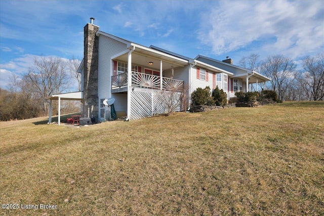 view of side of home featuring covered porch, a lawn, and a chimney