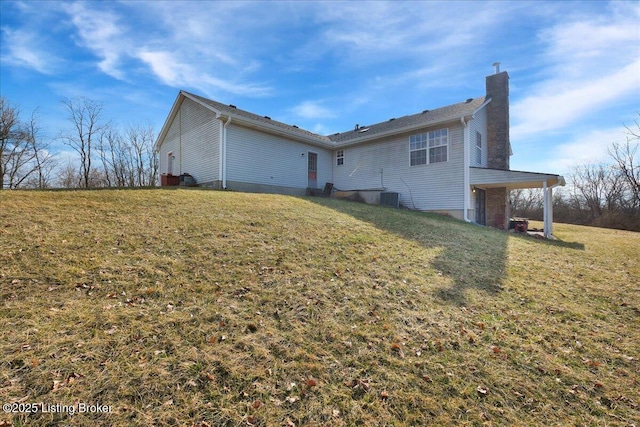 rear view of property featuring a chimney, central AC unit, and a yard