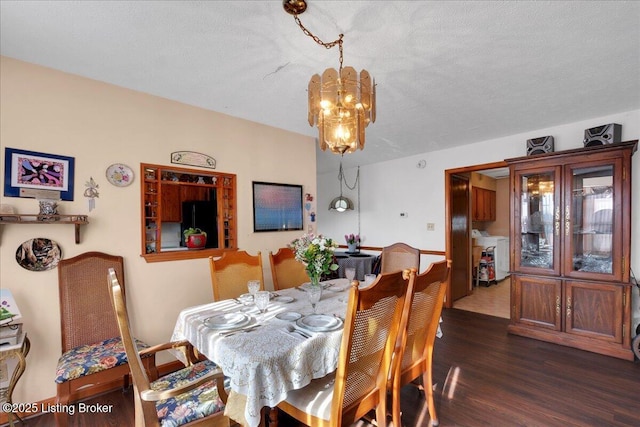 dining space with washer / dryer, a notable chandelier, a textured ceiling, and wood finished floors