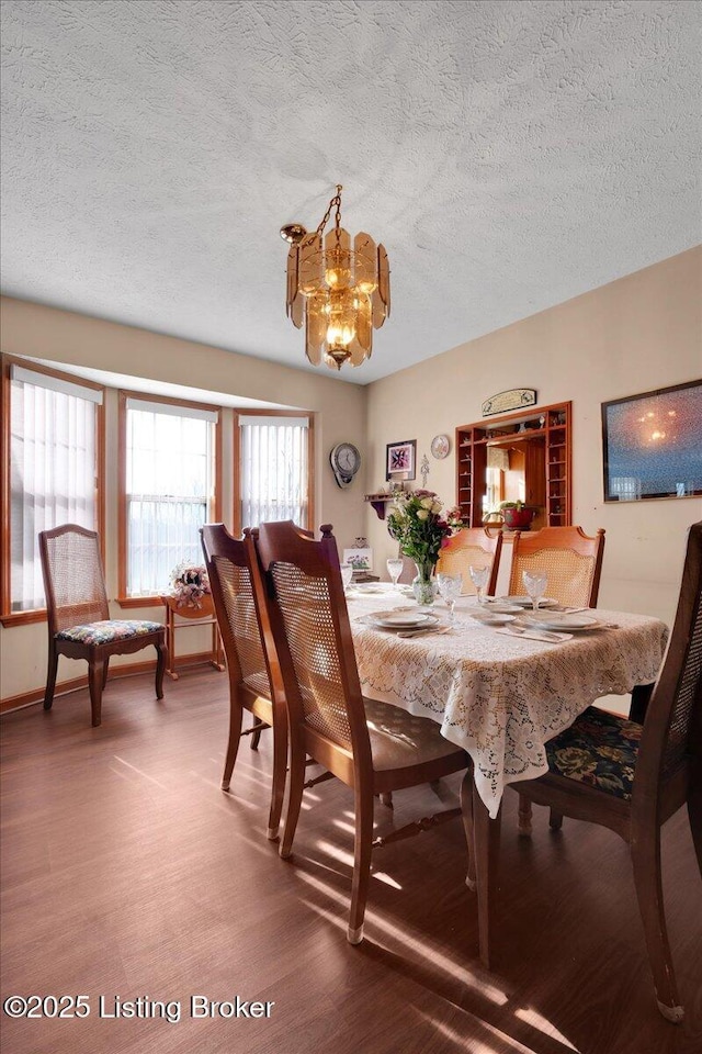 dining area with a textured ceiling, wood finished floors, and an inviting chandelier