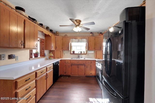 kitchen featuring dark wood finished floors, brown cabinetry, light countertops, black appliances, and a sink