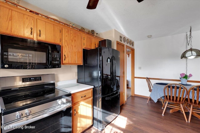 kitchen featuring light countertops, brown cabinetry, a textured ceiling, wood finished floors, and black appliances