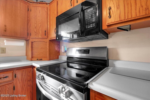 kitchen featuring brown cabinets, light countertops, black microwave, and stainless steel range with electric cooktop