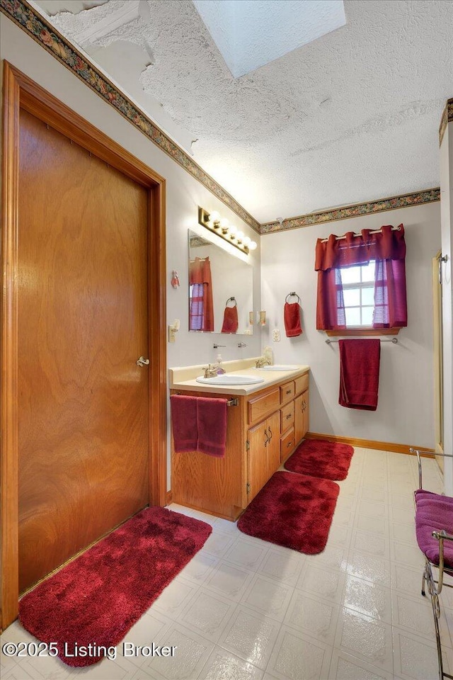 full bathroom with a sink, double vanity, a textured ceiling, and tile patterned floors