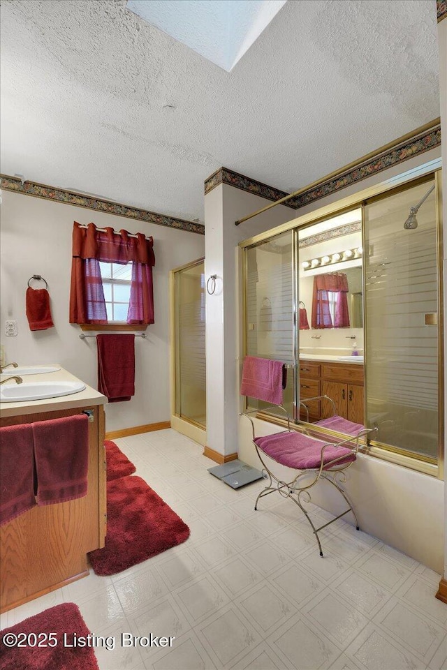 bathroom with a textured ceiling, vanity, a shower with shower door, and tile patterned floors