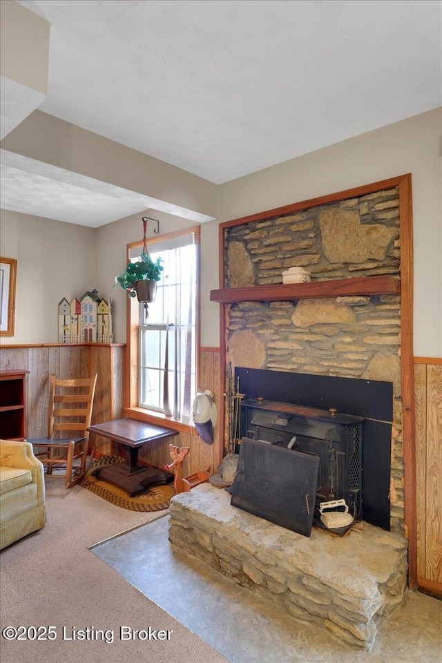 carpeted living room featuring a wainscoted wall, a fireplace, and wood walls