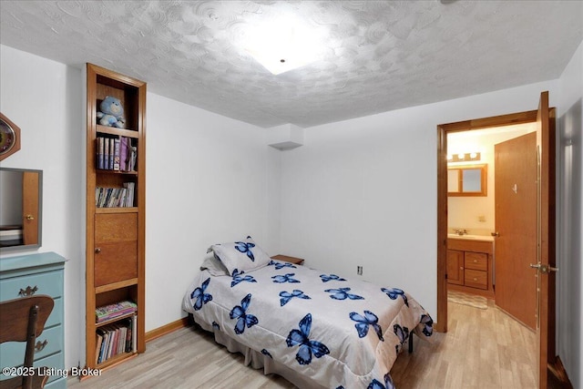 bedroom with ensuite bath, a textured ceiling, and light wood finished floors