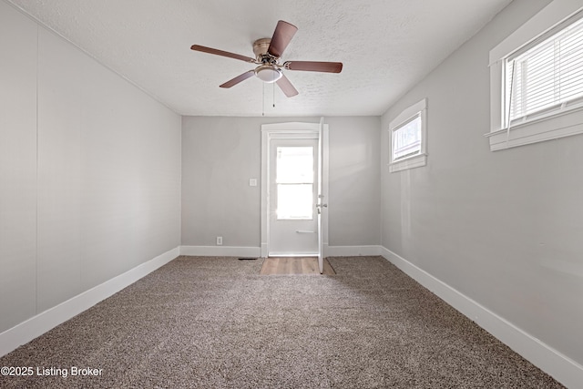 carpeted empty room featuring a ceiling fan, a textured ceiling, and baseboards