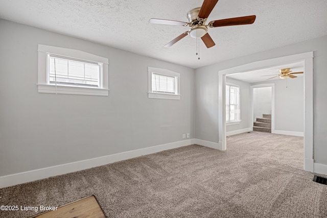 carpeted spare room with visible vents, ceiling fan, a textured ceiling, and baseboards