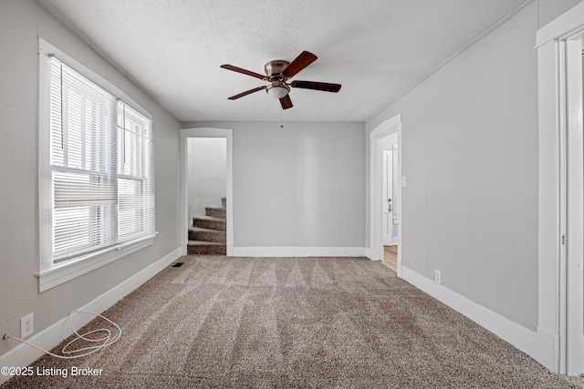 unfurnished room featuring a textured ceiling, carpet flooring, and baseboards