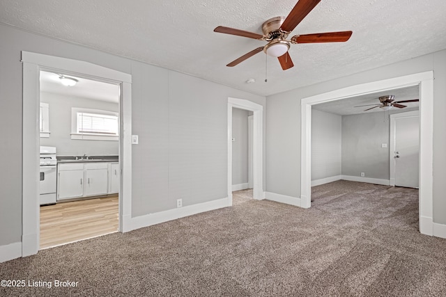 interior space with light carpet, ceiling fan, a textured ceiling, and baseboards