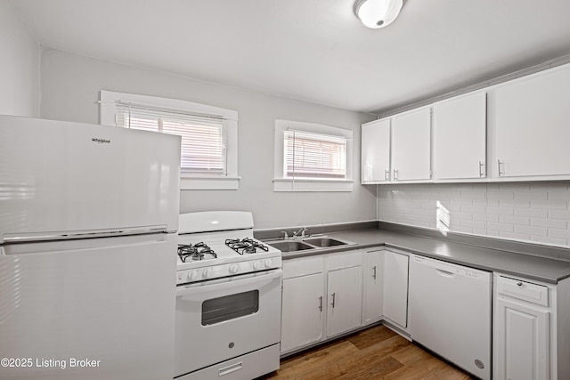 kitchen with white appliances, white cabinetry, a sink, and wood finished floors