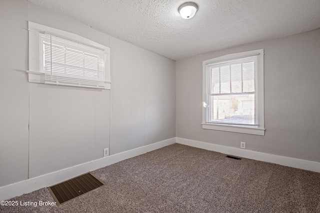 unfurnished room with baseboards, visible vents, a textured ceiling, and carpet flooring