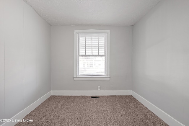 carpeted spare room with a textured ceiling, visible vents, and baseboards