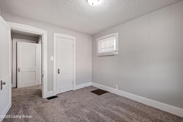 unfurnished bedroom with visible vents, a textured ceiling, baseboards, and carpet flooring