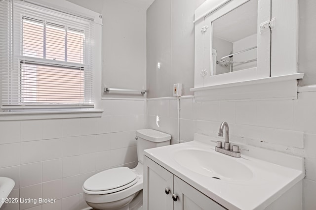 bathroom with vanity, toilet, and tile walls