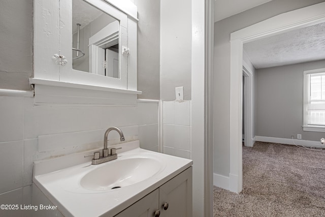 bathroom with a textured ceiling, vanity, and tile walls