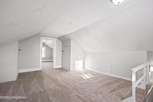 bonus room with carpet, baseboards, vaulted ceiling, and a textured ceiling