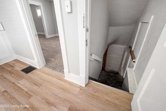 stairs featuring carpet, wood finished floors, visible vents, and baseboards