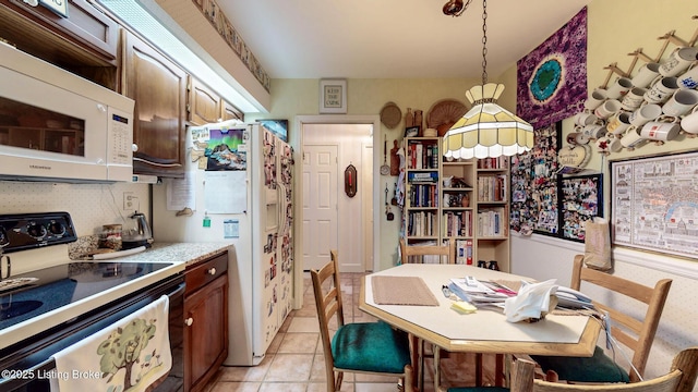 kitchen with light countertops, white appliances, light tile patterned flooring, and pendant lighting