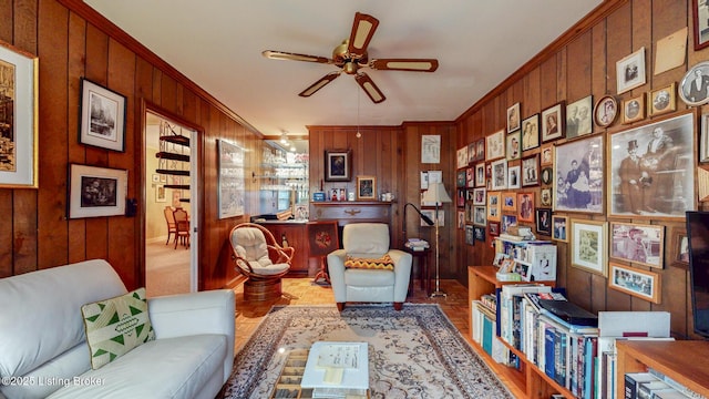 living area featuring ornamental molding, wood walls, and ceiling fan