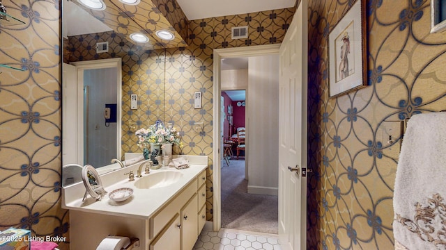 bathroom with wallpapered walls, baseboards, visible vents, and vanity