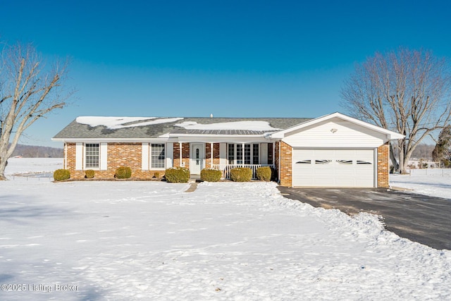 single story home featuring an attached garage, covered porch, aphalt driveway, and brick siding