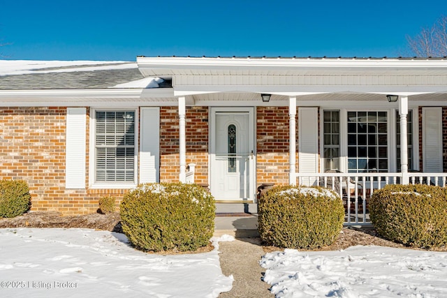 entrance to property featuring brick siding and a porch