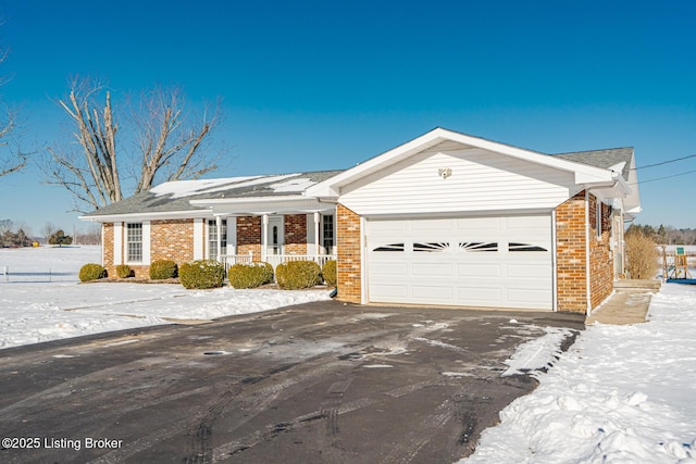 ranch-style home featuring driveway, covered porch, an attached garage, and brick siding