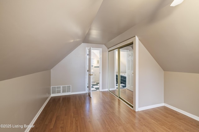 bonus room with visible vents, baseboards, vaulted ceiling, and wood finished floors