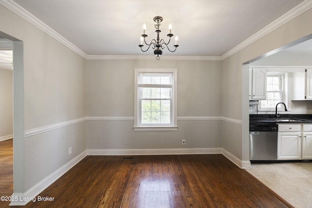 unfurnished dining area with baseboards, a chandelier, crown molding, a sink, and wood finished floors