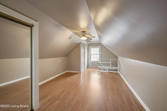bonus room featuring lofted ceiling, light wood-type flooring, baseboards, and ceiling fan