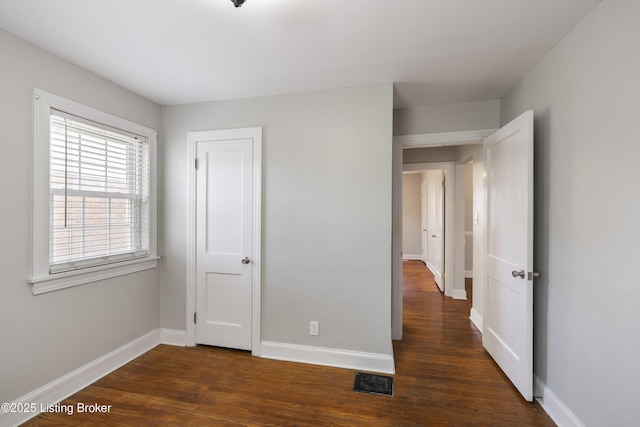 unfurnished bedroom featuring visible vents, baseboards, and wood finished floors