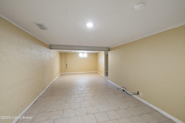 below grade area with a textured wall, visible vents, baseboards, and ornamental molding